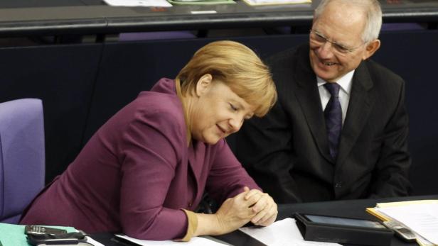 German Chancellor Angela Merkel and Finance Minister Wolfgang Schaeuble smile before a vote on financial help for Greece at the lower house of parliament, the Bundestag, in Berlin November 30, 2012. German lawmakers approved by a large majority on Friday a package of measures aimed at cutting Greece&#039;s debt load to 124 percent by 2020. The vote was seen as a key test of Chancellor Angela Merkel&#039;s authority over her centre-right coalition ahead of federal elections next September. REUTERS/Wolfgang Rattay (GERMANY - Tags: POLITICS BUSINESS)