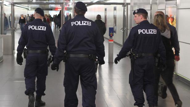 Drei Polizisten gehen in einer Unterführung entlang.