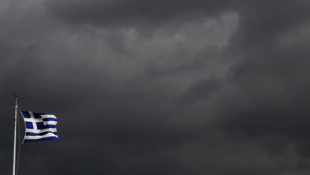 Die griechische Flagge weht vor einem dunklen, bewölkten Himmel.