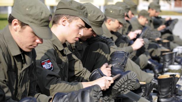 Eine Reihe von Soldaten in Uniform putzt ihre Stiefel.
