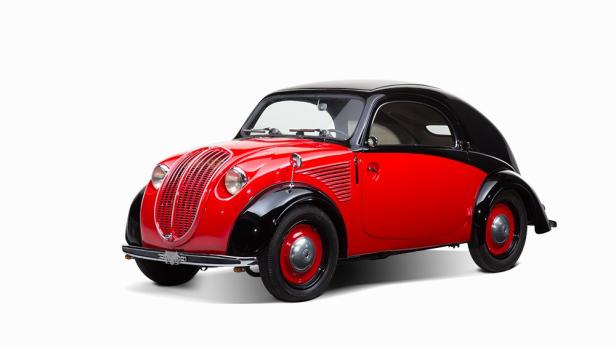 Ein rot-schwarzer Oldtimer vor einem weißen Hintergrund.