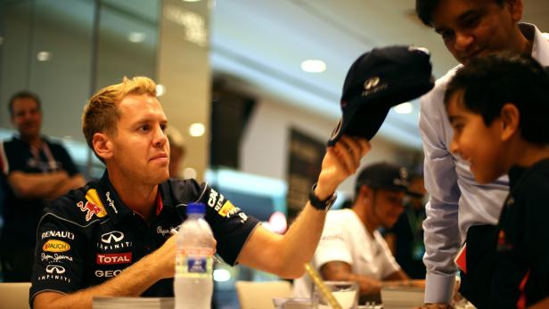 Sebastian Vettel signiert eine Kappe für einen jungen Fan.