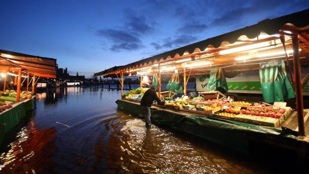 Ein überfluteter Marktstand mit Obst und Gemüse im Abendlicht.