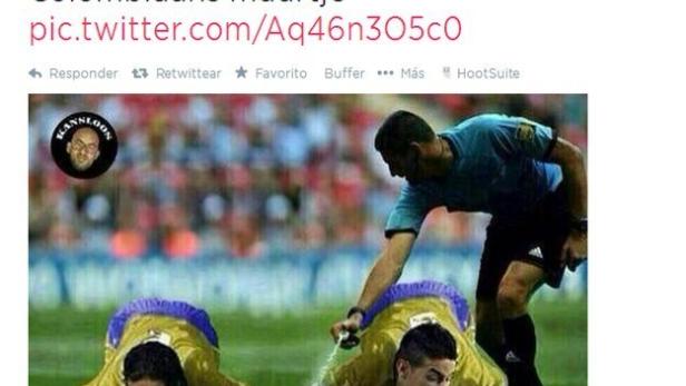 Ein Schiedsrichter sprüht Wasser in die Münder zweier kolumbianischer Fußballspieler, die auf dem Rasen liegen.