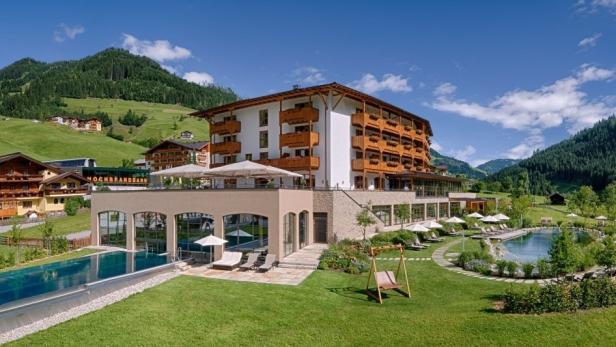 Ein Hotelresort mit Pools und Liegestühlen vor einer grünen Hügellandschaft.