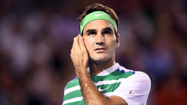 Roger Federer mit einem grünen Stirnband berührt sein Gesicht.