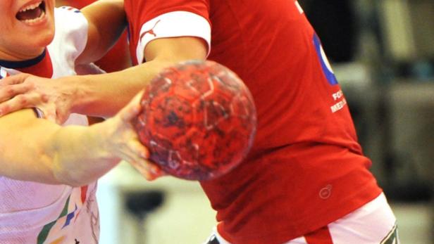 Zwei Handballspieler kämpfen um einen roten Handball.