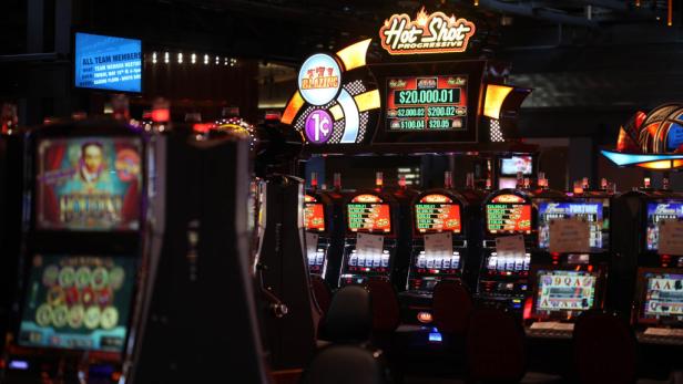 Mehrere Spielautomaten in einem Kasino, darunter ein „Hot Shot Progressive“-Automat mit hohen Jackpots.