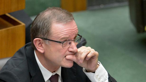 Ein Mann mit Brille kaut nachdenklich auf seinen Fingern.