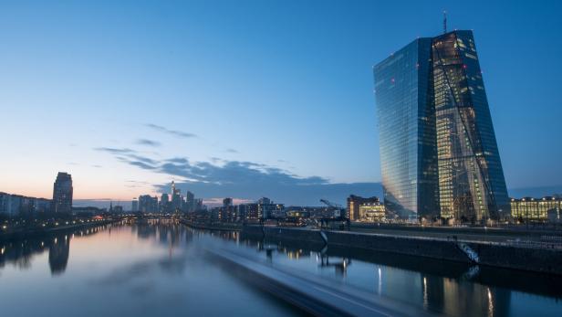 Die Skyline von Frankfurt am Main mit der Europäischen Zentralbank am Flussufer bei Dämmerung.
