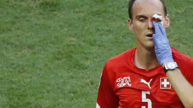 Ein verletzter Schweizer Fußballspieler wird auf dem Spielfeld behandelt.