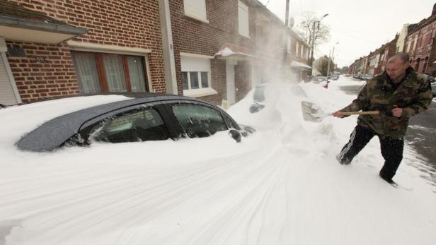 A man shovels snow off his car in a street of Cambrai, northern France, March 12, 2013 as winter weather with snow and freezing temperatures returns to northern France. REUTERS/Pascal Rossignol (FRANCE - Tags: ENVIRONMENT)