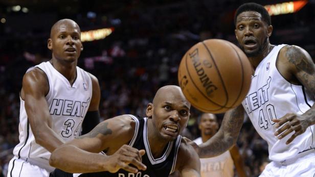 Drei Basketballspieler während eines Spiels auf dem Spielfeld.