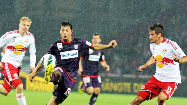 Ein Fußballspieler schießt bei Regenwetter auf dem Spielfeld einen Ball.