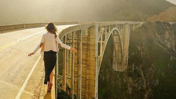 Eine Frau balanciert auf der Kante der Bixby Creek Bridge in Kalifornien.