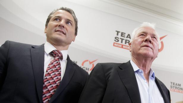 Zwei Männer in Anzügen blicken nach oben.