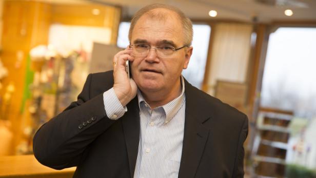 Ein Mann mit Brille und Anzug telefoniert mit einem Smartphone.