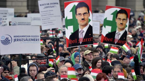 Eine Menschenmenge demonstriert mit ungarischen Flaggen und Schildern, einige davon mit Hitler-Bärten und der Aufschrift „Heil Marci!“.