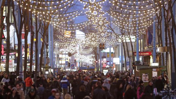 Eine belebte Straße mit Weihnachtsbeleuchtung und vielen Menschen.