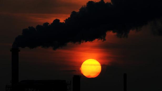 Die Sonne geht am 31.10.2012 hinter einem rauchenden Schornstein einer Industrieanlage in Wismar (Mecklenburg-Vorpommern) unter. Foto: Daniel Reinhardt/dpa +++(c) dpa - Bildfunk+++