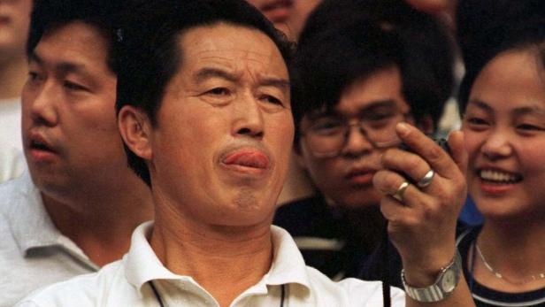 Eine Gruppe asiatischer Menschen, von denen einer seine Zunge herausstreckt und ein anderer ein Foto macht.