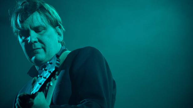 Ein Mann spielt Gitarre in blauem Licht.