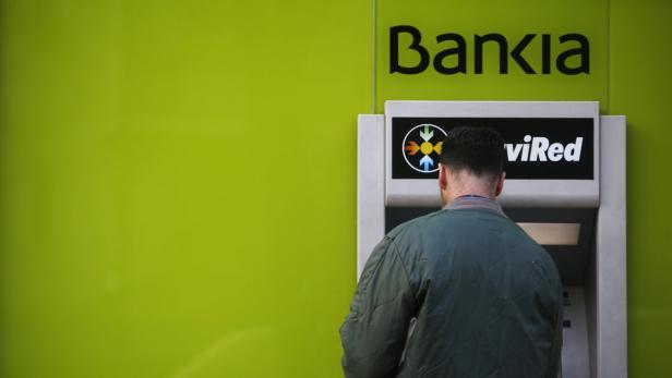 A man uses an ATM machine at a branch of Spain&#039;s nationalized lender Bankia in Madrid November 28, 2012. Spain&#039;s four nationalised banks will more than halve their balance sheets in five years, slash jobs and impose hefty losses on bondholders, under plans approved by the European Commission on Wednesday. REUTERS/Susana Vera (SPAIN - Tags: BUSINESS)