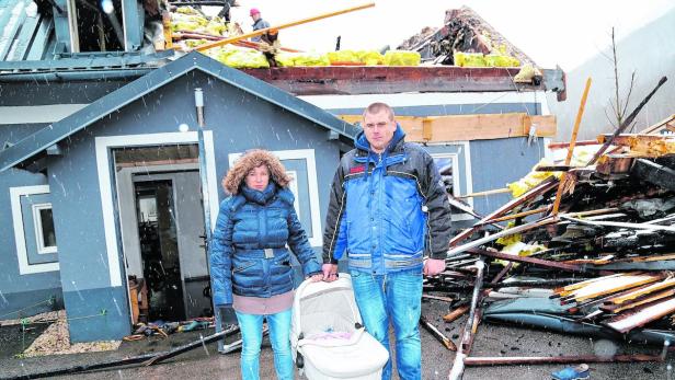 Daniela und Steffen Braun mit Töchterchen Lea vor ihrem von Feuer und Löschwasser zerstörten Haus in Ebensee