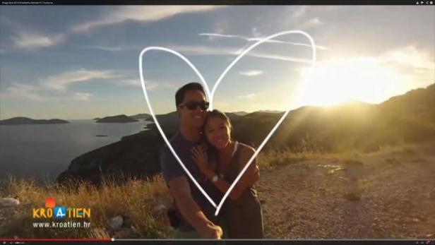 Ein Paar umarmt sich vor einer Küstenlandschaft in Kroatien, umrahmt von einem Herz.