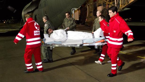 APA10497632-2 - 03122012 - HÖRSCHING - ÖSTERREICH: ZU APA-TEXT AI - Sanitäter tragen die Bahre mit einem der verletzten Soldaten, die am vergangenen Donnerstag im UNO Einsatz in Syrien angeschossen wurden, am Montag, 03. Dezember 2012, bei der Ankunft mit einem Transportflugzeugt des österreichischen Bundesheeres am Flughafen Hörsching. APA-FOTO: BUNDESHEER/SIMADER