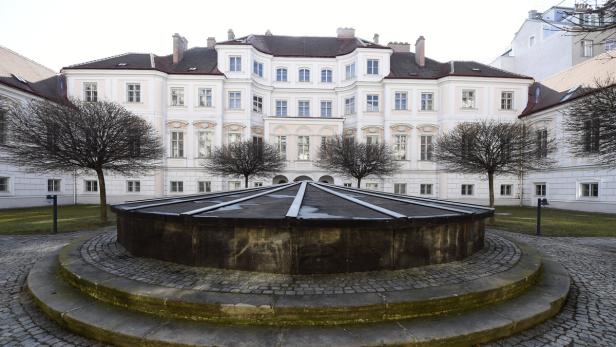 Ein Brunnen im Hof eines hellen, mehrstöckigen Gebäudes.