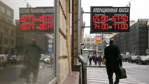Ein Mann überquert eine Straße in Russland vor einer Wechselkursanzeige.