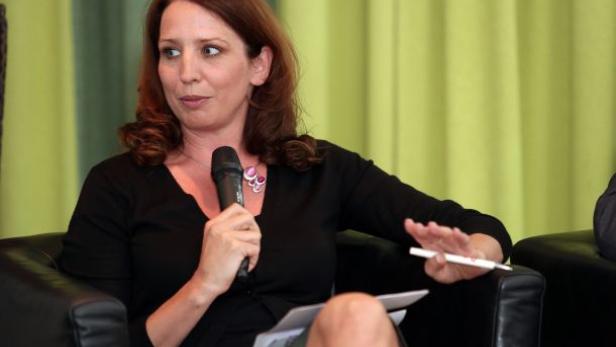 Eine Frau mit Mikrofon spricht während einer Podiumsdiskussion.