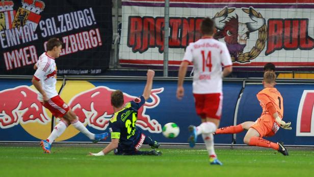 Fussball, Red Bull Salzburg - WAC Ein Fußballspiel mit Spielern in roten und blauen Trikots, der Torwart in Orange versucht, den Ball abzuwehren.