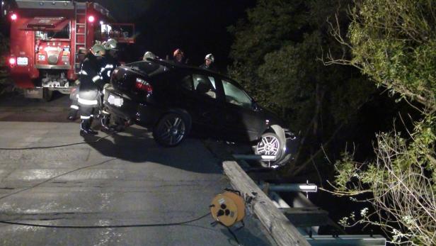 Ein schwarzes Auto ist verunglückt und wird von der Feuerwehr geborgen.