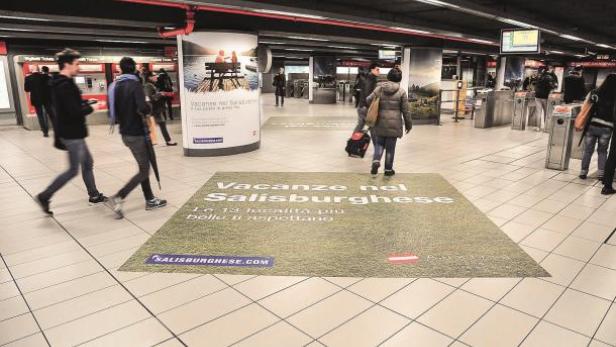 In einer U-Bahn-Station wirbt eine Bodenwerbung für Urlaube im Salisburghese.