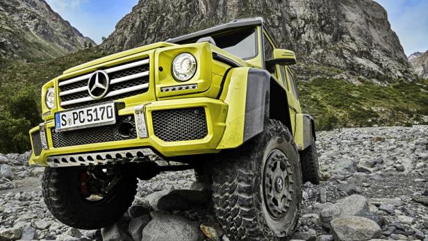 Ein gelber Mercedes-Benz G 500 4x4² steht auf einem steinigen Untergrund vor einer Bergkulisse.