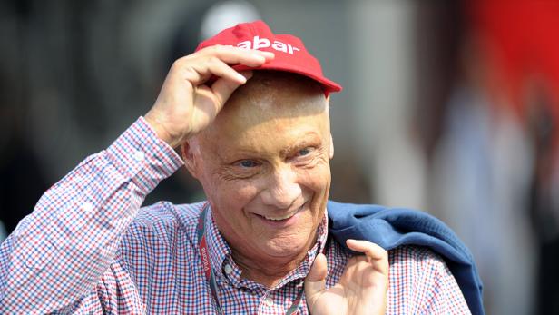 Niki Lauda mit roter Kappe und kariertem Hemd lächelt.