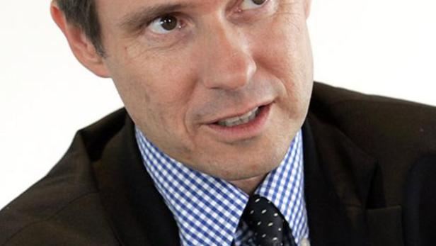 Ein Mann in Anzug und Krawatte gestikuliert mit den Händen.