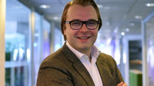 Ein Mann mit Brille und Sakko lächelt in die Kamera.