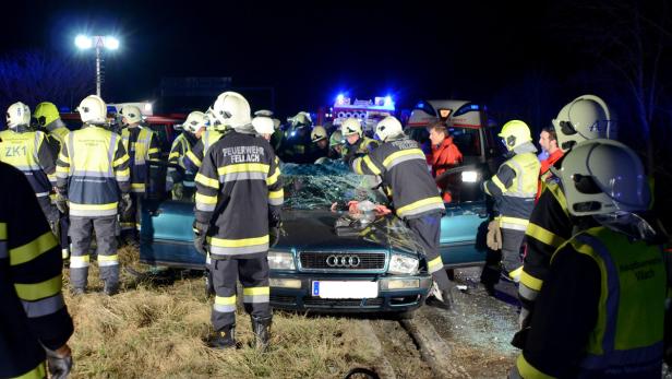 Feuerwehrleute arbeiten an einem Auto mit zerbrochener Windschutzscheibe nach einem Unfall.