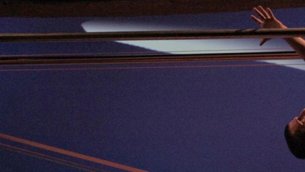 Ein Mann hängt an einer Stange vor einem blauen Hintergrund.