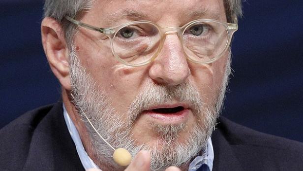 Ein Mann mit Brille und grauem Bart spricht in ein Mikrofon.