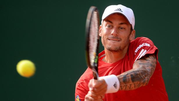 Ein Tennisspieler schlägt einen gelben Tennisball.