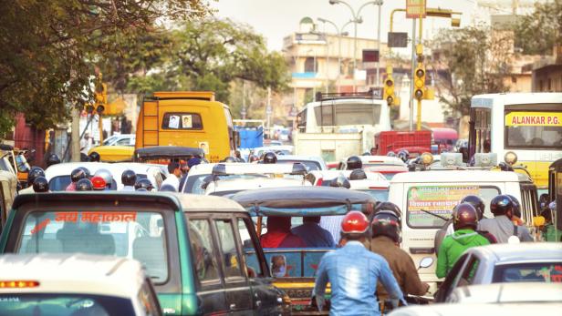 Dichter Verkehr mit Autos, Motorrädern und Bussen in einer indischen Stadt.