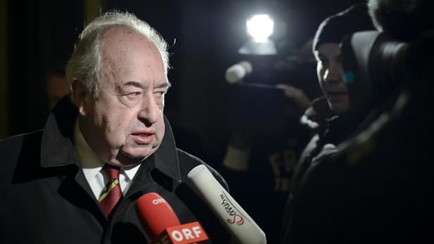 Ein Mann wird von Reportern mit Mikrofonen interviewt.