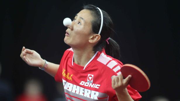 Eine Tischtennisspielerin balanciert einen Ball auf ihrer Nase.