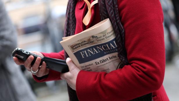 epa03483610 An employee of publishing house Gruner + Jahr Business Media wears a salmon ribbon and carries the current issue of the &#039;Financial Times Germany&#039; (FTD) in fornt of the publishing house&#039;s headquarters in hamburg, Germany, 23 November 2012. Gruner + Jahr discontinue their daily business newspaper &#039;Financial Times Germany&#039;. EPA/CHRISTIAN CHARISIUS