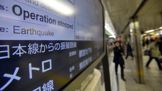 epa03499781 Commuters walk past a screen announcing delayed train lines due to an earthquake that struck northeastern Japan at Ikebukuro station in Tokyo, Japan, 07 December 2012. A 7.3 magnitude earthquake struck northeastern Japan in late afternoon. Tsunami warnings were issued but no immediate damage were reported. EPA/FRANCK ROBICHON