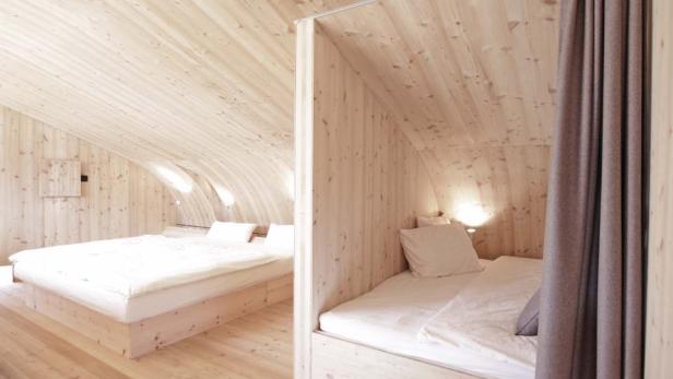 Zwei Betten in einem Zimmer mit Holzwänden und gewölbter Decke.